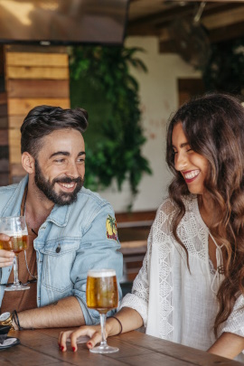 Lachendes Paar sitzt im Biergarten und trinkt
