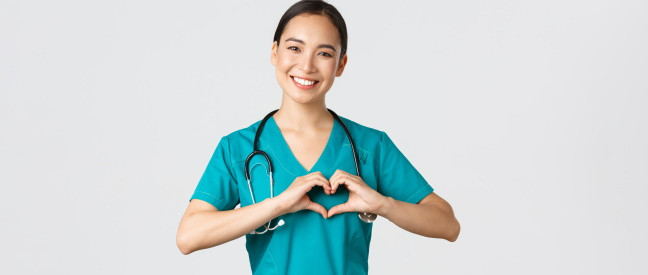 Junge Krankenschwester macht Herz-Geste mit Händen