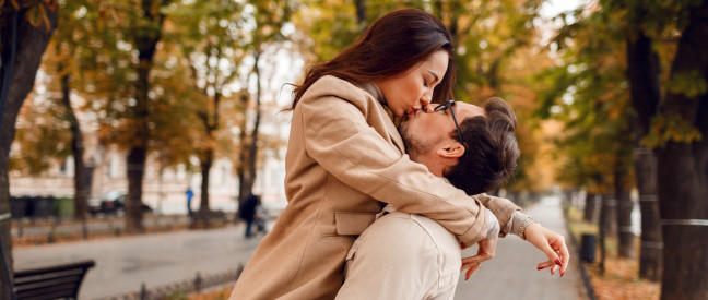 Frau umarmt Mann und küsst ihn am Straßenrand