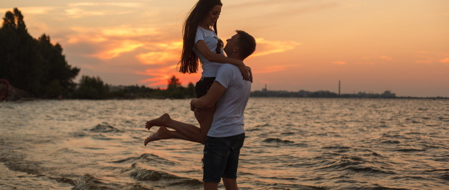 Paar umarmt sich beim Date abends am Strand