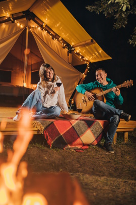 Paar sitzt draußen vor der Hütte am Lagerfeuer