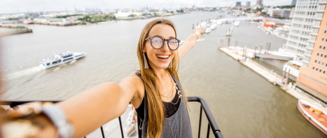 Frau beim Date zeigt lachend auf Hamburger Hafen