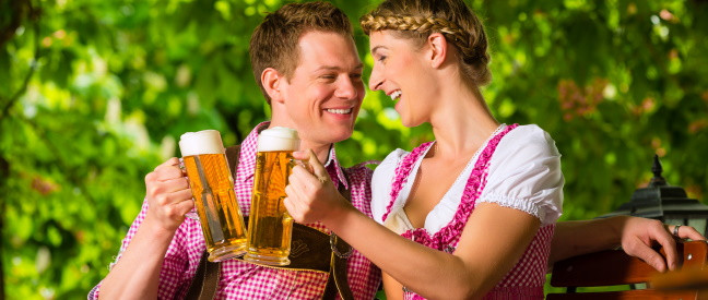 Mann und Frau stoßen mit Maßkrügen im Biergarten an