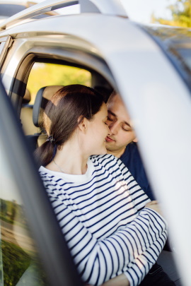 Mann und Frau küssen im Auto bei geöffneter Tür