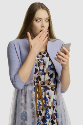 Frau am Handy ist schockiert über Nachricht