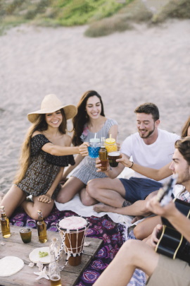 Freunde sitzen am Strand und trinken