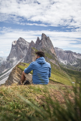 Mann auf Wanderung schaut sitzend in die Berge