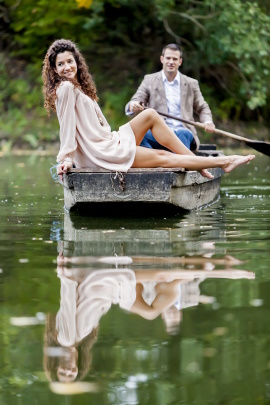 Fröhliches Paar sitzt auf Floß und der Mann rudert