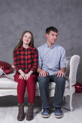 Mann sitzt schüchtern neben Frau auf dem Sofa