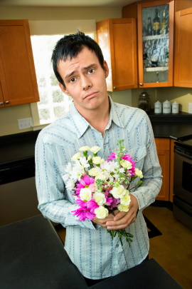 Mann schenkt Frau Blumen mit unterwürfigem Blick