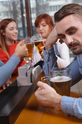 Mann sitzt alleine mit Bier in der Bar