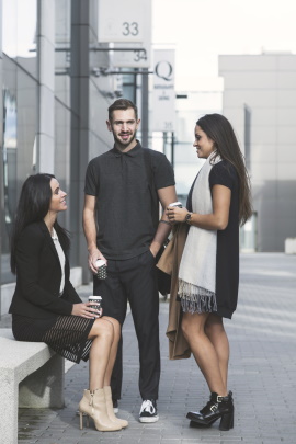 Schüchterner Mann steht mit zwei Frauen vor Bürogebäude