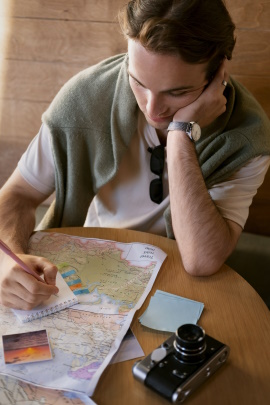 Mann mit Landkarte macht Notizen auf einem Schreibblock
