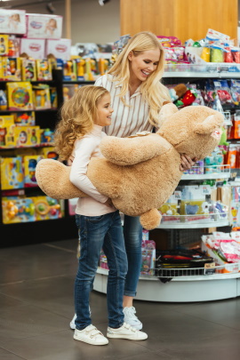 Mutter und Tochter im Spielzeugladen bewundern großen Teddybär