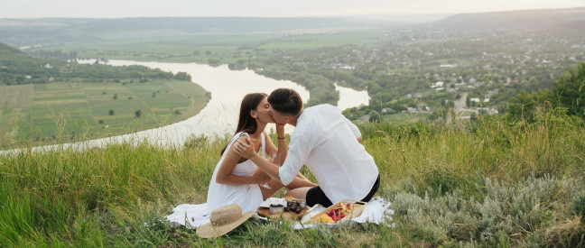 Paar küsst sich bei romantischem Picknick-Date am Fluss