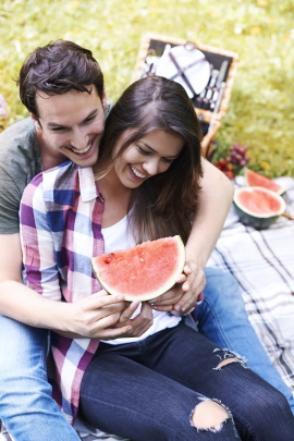 Paar sitzt beim Picknick im Park und isst Melone