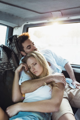 Paar mit Wolldecke liegt schlafend im Auto