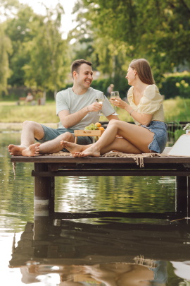 Mann und Skorpionfrau beim Date am See machen Picknick auf dem Steg