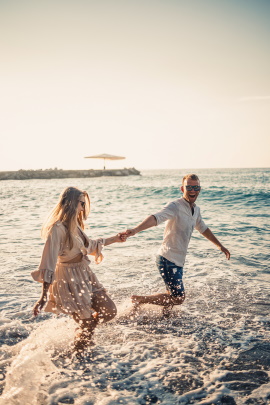 Mann und Frau laufen lachend durchs Wasser