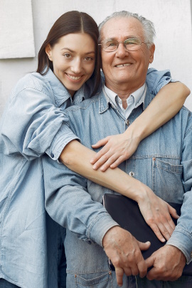 Junge Frau umarmt alten Mann