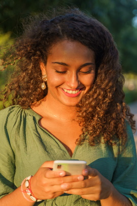 Frau mit Smartphone lacht über Tinder-Nachricht
