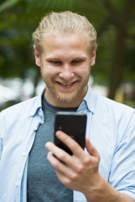 Mann schaut glücklich aufs Handy, weil Tinder entsperrt wurde
