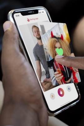 Mann wischt am Smartphone durch Profile einer Dating-App