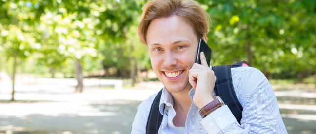 Mann telefoniert fröhlich mit Handy im Park