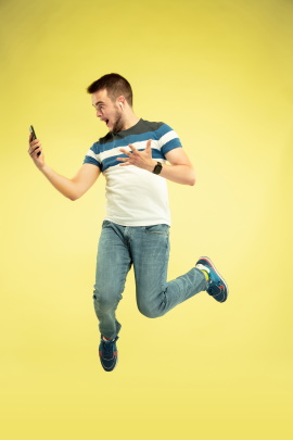 Mann mit Handy springt vor Freude in die Luft