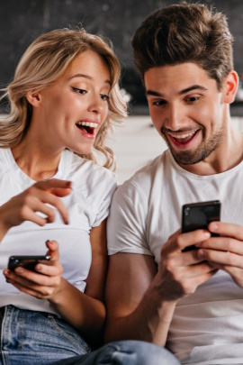 Paar schaut begeistert aufs Handy des jeweils anderen