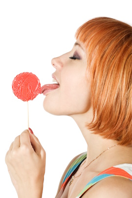 Frau leckt an rotem Lutscher mit herausgestreckter Zunge