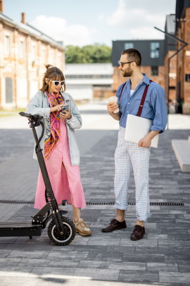 Frau mit E-Scooter redet mit Mann auf der Straße