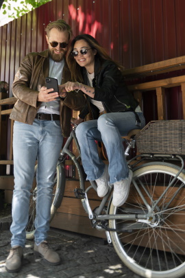 Frau mit Fahrrad tippt auf dem Smartphone des Mannes