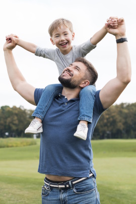 Vater trägt lachenden Sohn auf seinen Schultern