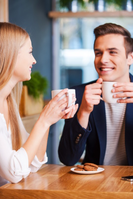Paar sitzt lachend im Café und trinkt Kaffee