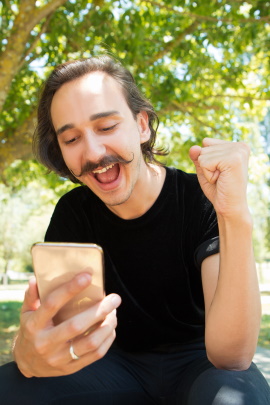 Mann mit Handy freut sich über Matches bei Tinder