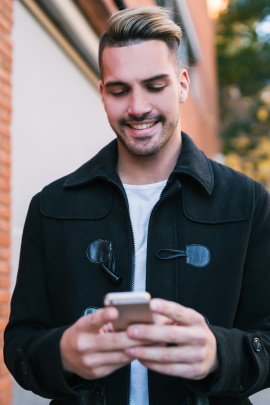 Mann schaut lächelnd aufs Smartphone