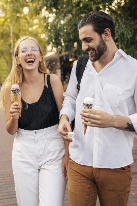 Mann und Frau mit Eis laufen lachend durch den Park