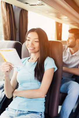 Frau liest Buch während einer Busreise