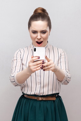 Frau schaut entsetzt aufs Handy und liest Nachricht