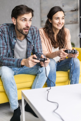 Paar sitzt auf dem Sofa mit Gamepads und spielt Videospiel
